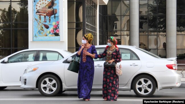 Женщины в защитных масках для лица, которые используются в качестве превентивной меры против распространения коронавирусной болезни (COVID-19), переходят дорогу в Ашгабате. Туркменистан, 15 июля 2020 года.