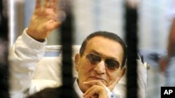 Bivši egipatski predsjednik Hosni Mubarak maše svojim pristalicama iza rešetaka na saslušanju tokom obnovljenog suđenja u Kairu, 13. aprila 2013.