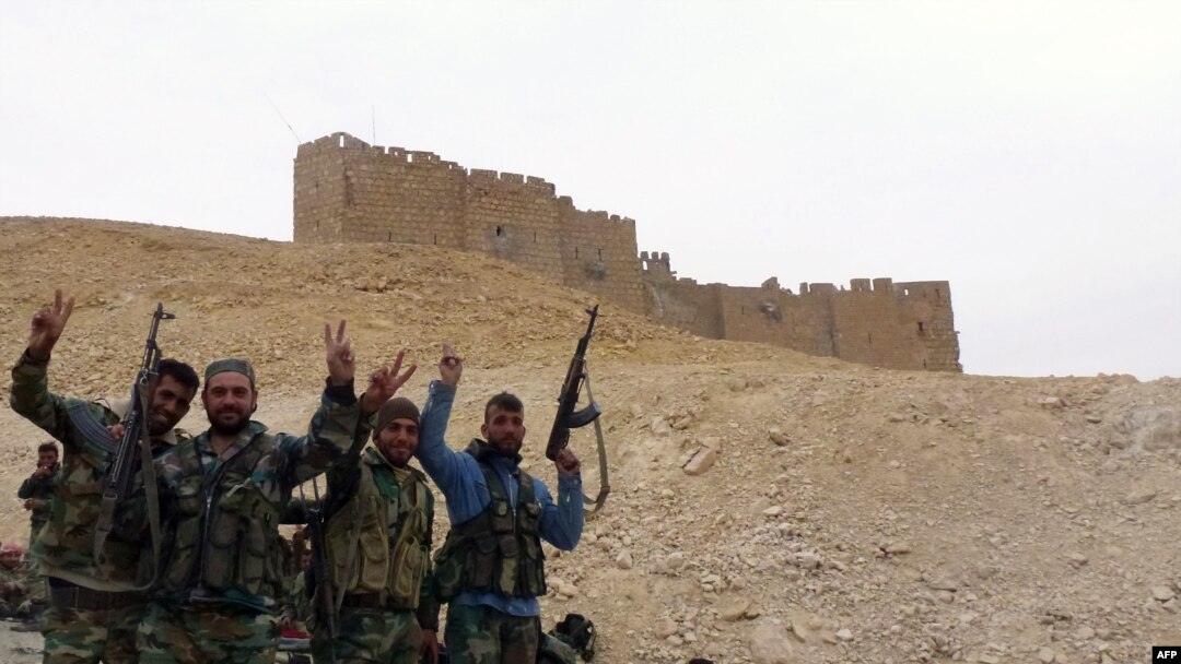 Syrian pro-governement forces gesture next to the Palmyra citadel during a military operation to retake the ancient city from the extremist Islamic State group. 
