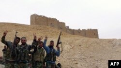 Syrian pro-governement forces gesture next to the Palmyra citadel during a military operation to retake the ancient city from the extremist Islamic State group. 