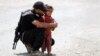 An Iraqi soldier helps a displaced girl near Mosul.