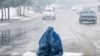 A burqa-clad Afghan woman looks for alms on a street during the first heavy snowfall this winter in Kabul.&nbsp;