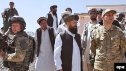 Polish Foreign Minister Radoslaw Sikorski (right) stands with governor of Ghazni Province Musa Khan Akbarzada (center) as he visited reconstruction work and Polish soldiers in Afghanistan in June 2010.