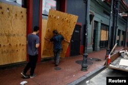 Muškarci postavljaju šperploču ispred trgovine u pripremi za uragan Ida, u New Orleansu, Louisiana, 28. augusta 2021.