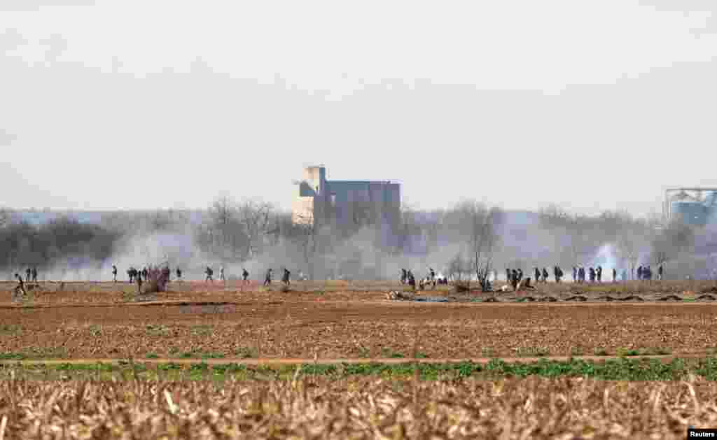 Migrants engulfed in a cloud of tear gas near Turkey&#39;s Pazarkule border crossing on March 2. Greek government spokesman Stelios Petsas accused Turkey of trying to orchestrate a crisis and said &quot;this movement is guided and encouraged by Turkey.&quot;