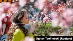 Një vajzë heq maskën për t’iu marrë erë luleve. Shkup,mars, 2020. 