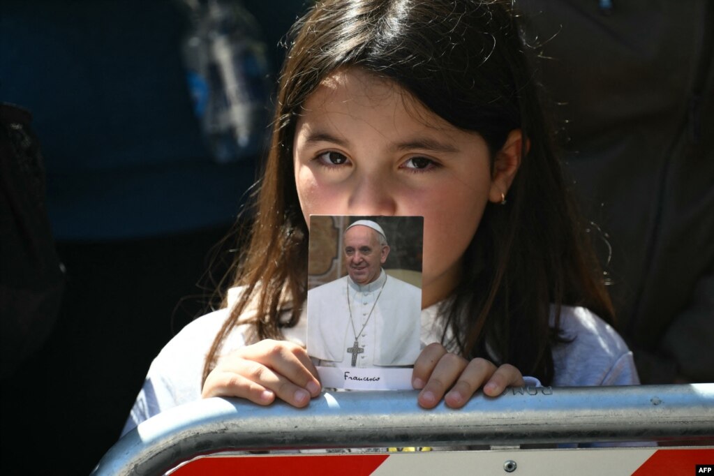 Një besimtare e re mban një fotografi të Papa Françeskut të ndjerë ndërsa pret gjatë ceremonisë së varrimit të tij, në qendër të Romës.