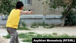 Мальчик играет в войну близ здания, где проходит суд по делу о расстреле демонстрантов в Жанаозене. Актау, 7 мая 2012 года. 