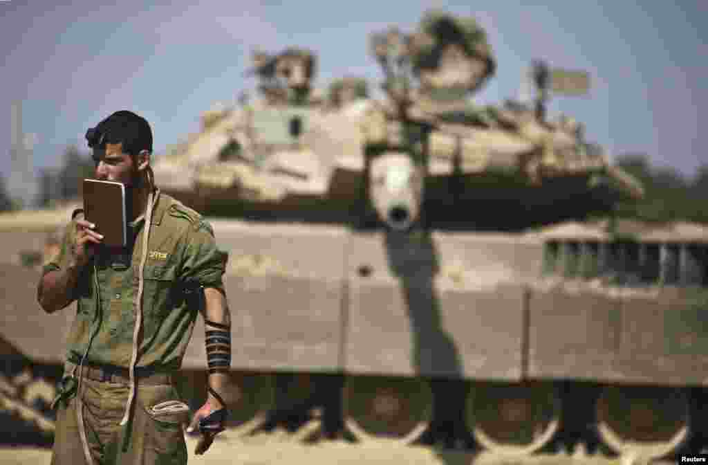 An Israeli soldier prays in front of a tank at a military staging area near the border with the Gaza Strip on July 24. (Reuters/Nir Elias)