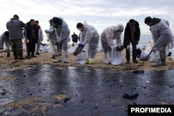 Munictorii curăță nisipul îmbibat cu petrol în stațiunea Anapa de la Marea Neagră, după ce petrolierele Volgoneft 212 și Volgoneft 239, încărcate cu 9.200 de tone de păcură, au naufragiat în strâmtoarea Kerci - decembrie 2024.
