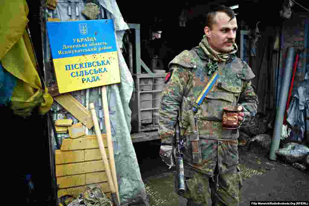 Украинский военный 93-й отдельной механизированной бригады отдыхает за кофе и сигаретой. Знак, снытй военными с Песковского сельского совета, висит на &laquo;Позиции 18&raquo;
