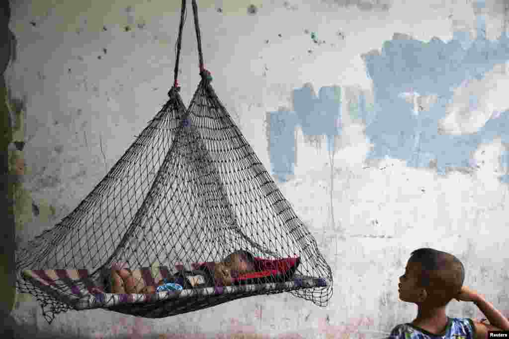 A son of a migrant fisherman from Burma rests in a hammock at a former shrimp warehouse where his family lives in Ban Nam Khem, Thailand. (Reuters/Damir Sagolj)