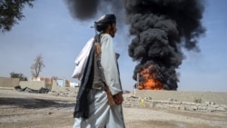 A Taliban fighter walks as smoke rises after Pakistani air strikes hit oil depots for commercial airlines, near the Kandahar airport in March. 
