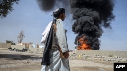 A Taliban fighter walks as smoke rises after Pakistani air strikes hit oil depots for commercial airlines, near the Kandahar airport in March. 