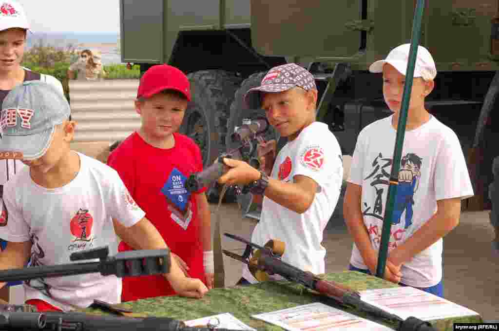Мальчик прицеливается из снайперской винтовки