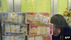 Iraqi dinars are stacked at a teller's window in a Najaf bank.