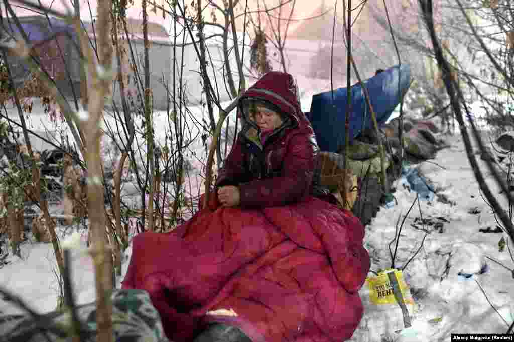 Lyusya Stepanova, 44, sits on a warm pipe after waking up. She is considering trying to return to society after more than 27 years on the streets. She was hospitalized earlier this year for three weeks with serious burns across her body after she fell asleep too close to the pipes where she was sheltering. She is now in a rehabilitation center 30 kilometers outside of town.