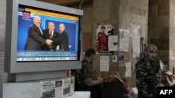Pro-Russian fighters of the Vostok Battalion stand next to a TV airing coverage of the creation of the Eurasian Economic Union, in the regional government building in Donetsk, May 29, 2014