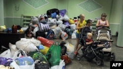 Children stand next to personal belongings in a hostel and temporary shelter organized for people displaced by ongoing violence in the eastern regions of Ukraine, in the small eastern city of Ilovaisk, in Donetsk region, on June 5.