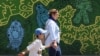 An Iranian woman and a child walk past a mural on a street in Tehran on September 2.