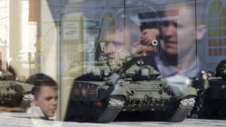 People are reflected in the glass of a bus stop as a Russian T-90 tank participates in the rehearsal for the Victory Day military parade on Red Square in Moscow.