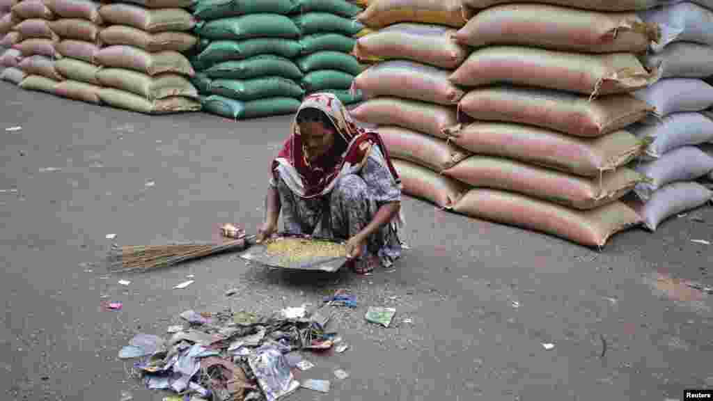 A Pakistani woman sorts out scraps of rice and lentils from a pile of waste near a supply warehouse at a wholesale market in Karachi on July 16. (REUTERS/Akhtar Soomro)