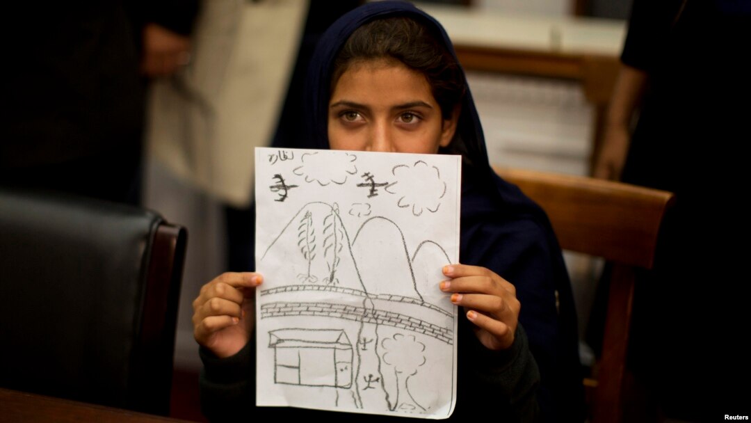 At a news conference in Washington on October 29, Nabila Rehman holds up a picture she drew depicting the U.S. drone strike on her Pakistani village which killed her grandmother.