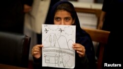 At a news conference in Washington on October 29, Nabila Rehman holds up a picture she drew depicting the U.S. drone strike on her Pakistani village which killed her grandmother.