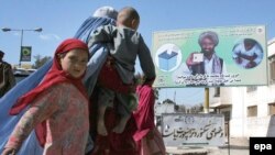 A family passes by an electoral billboard in Kabul
