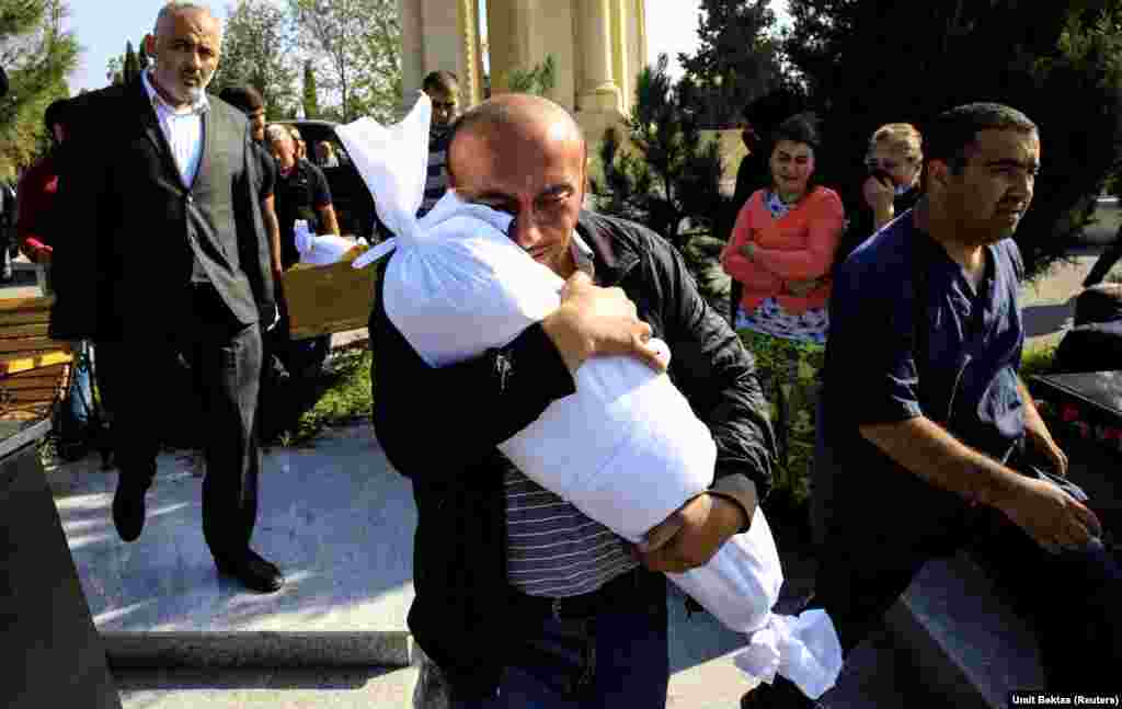 Timur Xaligov mban në duar trupin e pajetë të vajzës së tij 10-muajshe Narin. Ajo, së bashku me pesë anëtarë të tjerë të familjes, përfshirë nënën e saj, Sevil, pasi më 17 tetor një raketë goditi shtëpinë e tyre në qytetin azerbajxhanas Ganca, që gjendet në rajonin e shkëputur të Nagorno-Karabakut.(Reuters/Umit Bektas)