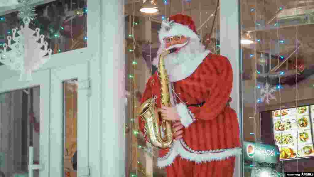 Зростова лялька Санта Клауса, який грає на саксофоні, біля входу в один із закладів громадського харчування на набережній Ялти
