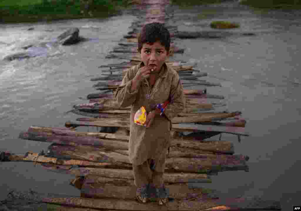 An Afghan refugee boy looks as he crosses a temporary wooden bridge at the Jalala refugee camp in Pakistan&#39;s Mardan district. (AFP/A Majeed)