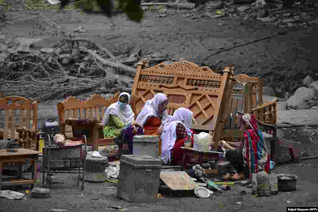 A family gathers around their belongings outside their damaged house following heavy monsoon rains in Neelum Valley, near the Line of Control in Pakistan-controlled Kashmir. In Pakistan-administered Kashmir, officials said at least 23 people were killed after heavy rain triggered flash floods and damaged more than 120 houses and 30 shops. (AFP/Sajjad Qayyum)