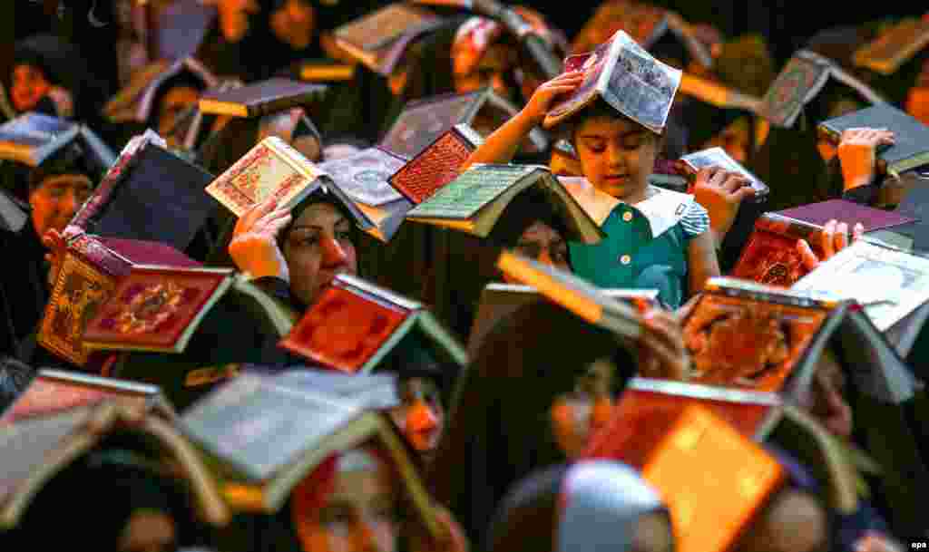 Shi'ite Muslims place copies of the Koran on their heads while gathering to read the holy Koran during the holy month of Ramadan at Imam Ali shrine in Al-Najaf, Iraq, on June 15. (epa/Khider Abbas)