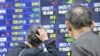 Pedestrians look at share prices on a board in Tokyo. Japan in the 1990s is an example of how "fiscal and monetary aspirin can kill the patient if used to treat a serious disease."