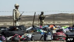 Egyptian Army soldiers stand guard next to the luggage and belongings of passengers from the Russian airliner piled up at the site of the crash in Wadi el-Zolmat, a mountainous area on the Sinai Peninsula.