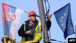 Serbia -- A worker arranges flags of Serbia and EU on a lamppost in Belgrade, 02Mar2012