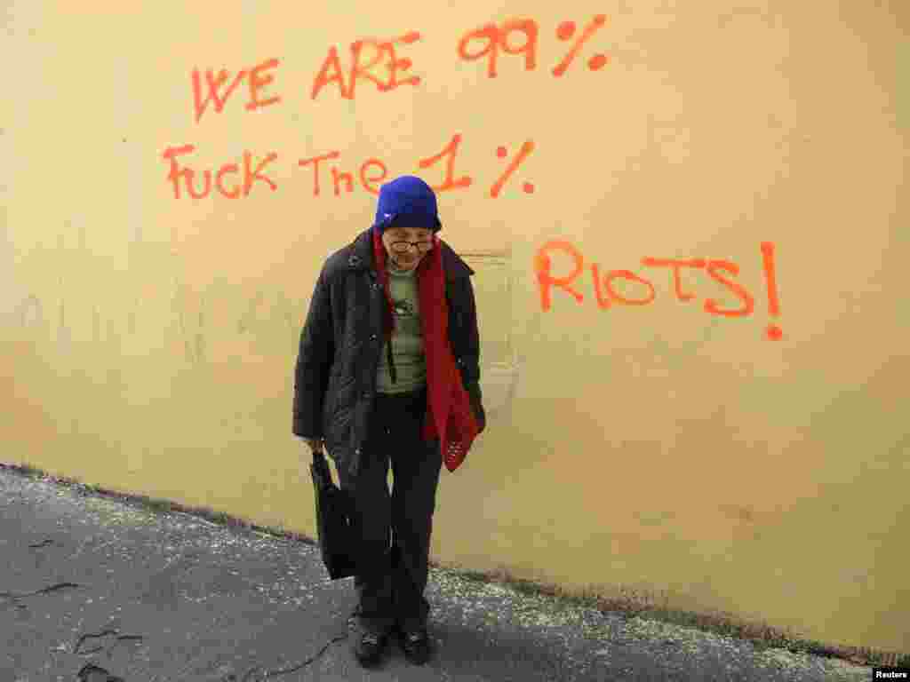 A woman walks past a wall with graffiti in Rome on November 15. (REUTERS/Stefano Rellandini)