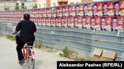 Велосипедист поминува покрај постери на владејачката партија за предвремените избори 2011. 