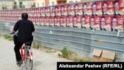 Велосипедист поминува покрај постери на владеачката партија за предвремените избори 2011