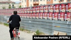 Велосипедист поминува покрај постери на владеачката партија за предвремените избори.