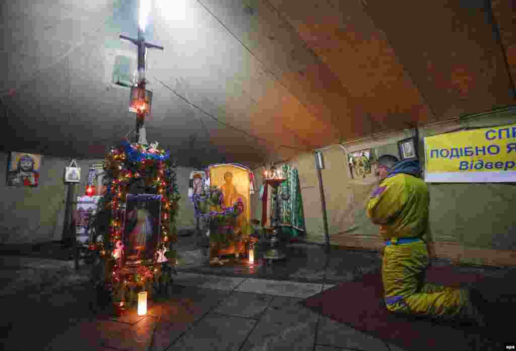 In Ukraine, a protester prays in an improvised church in a Ukrainian opposition camp tent on Independence Square in Kyiv on January 6, 2014.
