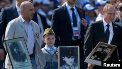 Russian President Vladimir Putin (right) holds a portrait of his father as he takes part in the Immortal Regiment march in Moscow on May 9.