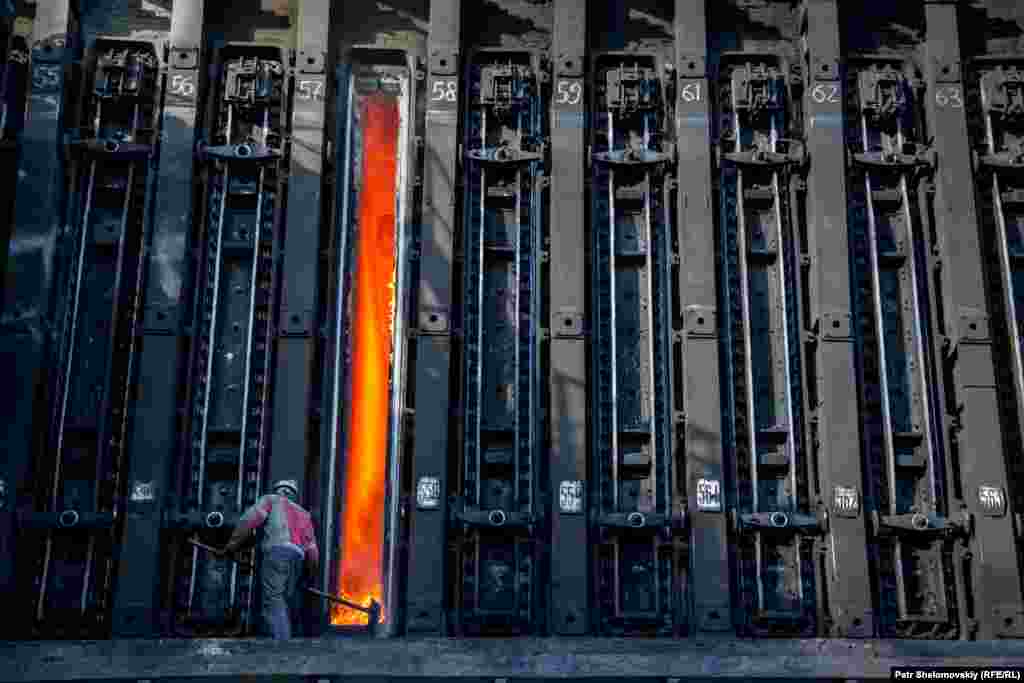 A worker shovels red hot coal.