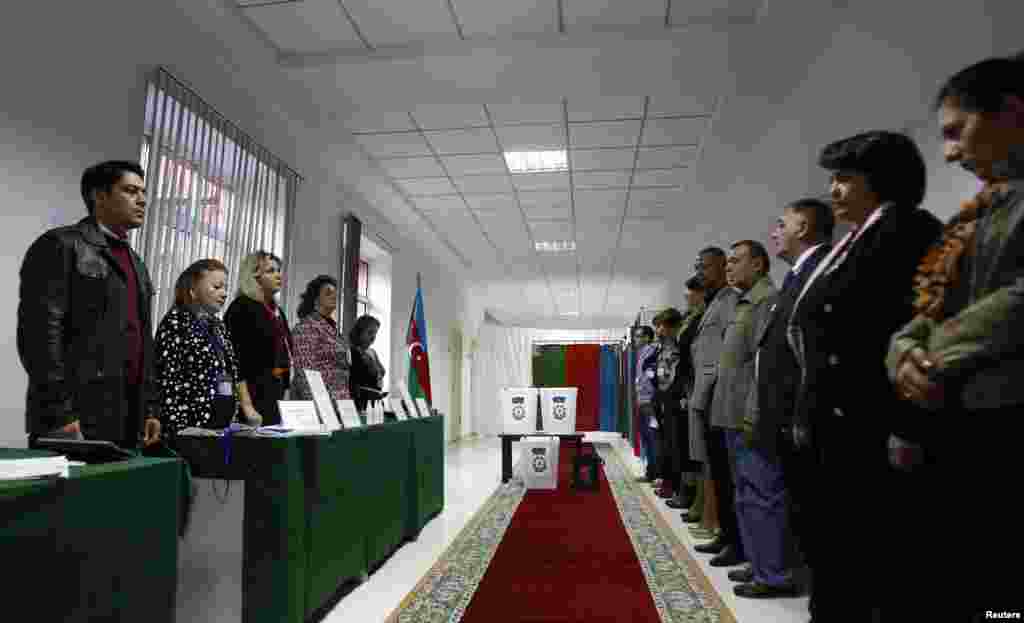 Election officials (left) and local observers listen to the national anthem as the polling station opens for voting in Azerbaijan's presidential election in Baku on October 9. (Reuters/David Mdzinarishvili)