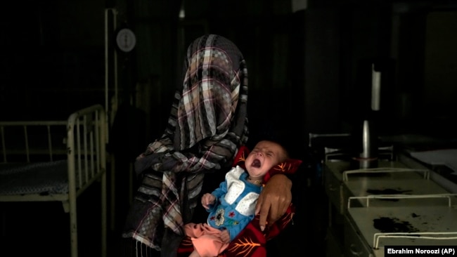 Nazia 30, e cila ka humbur katër fëmijë për shkak të kequshqyerjes së rëndë, mban fëmijën e saj të kequshqyer në një spital në provincën Parwan në veri të Kabulit, Afganistan më 2022.