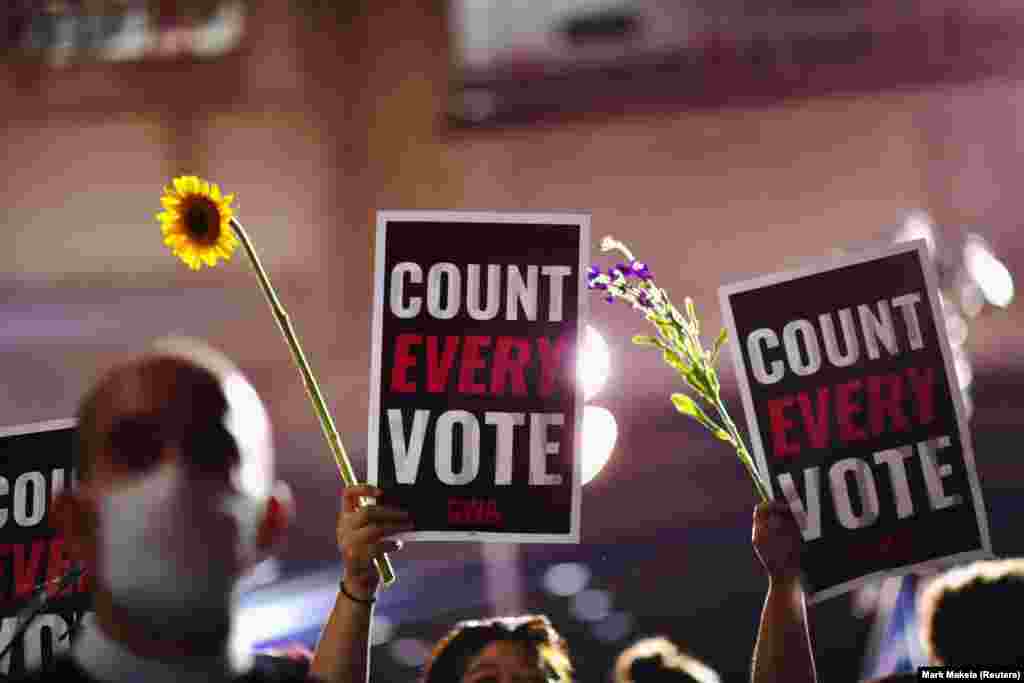 Activists hold up flowers and signs stating &quot;COUNT EVERY VOTE&quot; across the street from where votes are still being counted, two days after the 2020 U.S. presidential election, in Philadelphia, Pennsylvania, U.S. November 5, 2020. REUTERS/Mark Makel