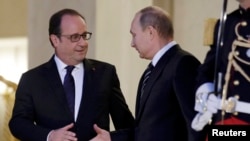 French President Francois Hollande (left) shakes hands with Russian President Vladimir Putin after a summit on the Ukraine crisis at the Elysee Palace in Paris, France, on October 2.