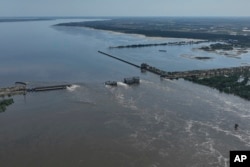 Вода течет через разрушенную дамбу Каховской ГЭС в оккупированной военными РФ Новой Каховке, 7 июня 2023 года