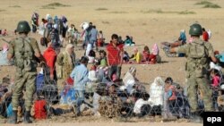 Сирийские беженцы сидят возле турецко-сирийской границы после бегства из Сирии. Турецкий город Суруч, 19 сентября 2014 года.